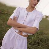 Woman wearing a white outfit with ruffled details in a natural setting