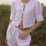 Woman wearing a white linen outfit with a blurred natural background