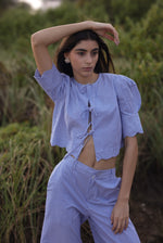 Woman wearing a blue checkered outfit standing in a natural setting