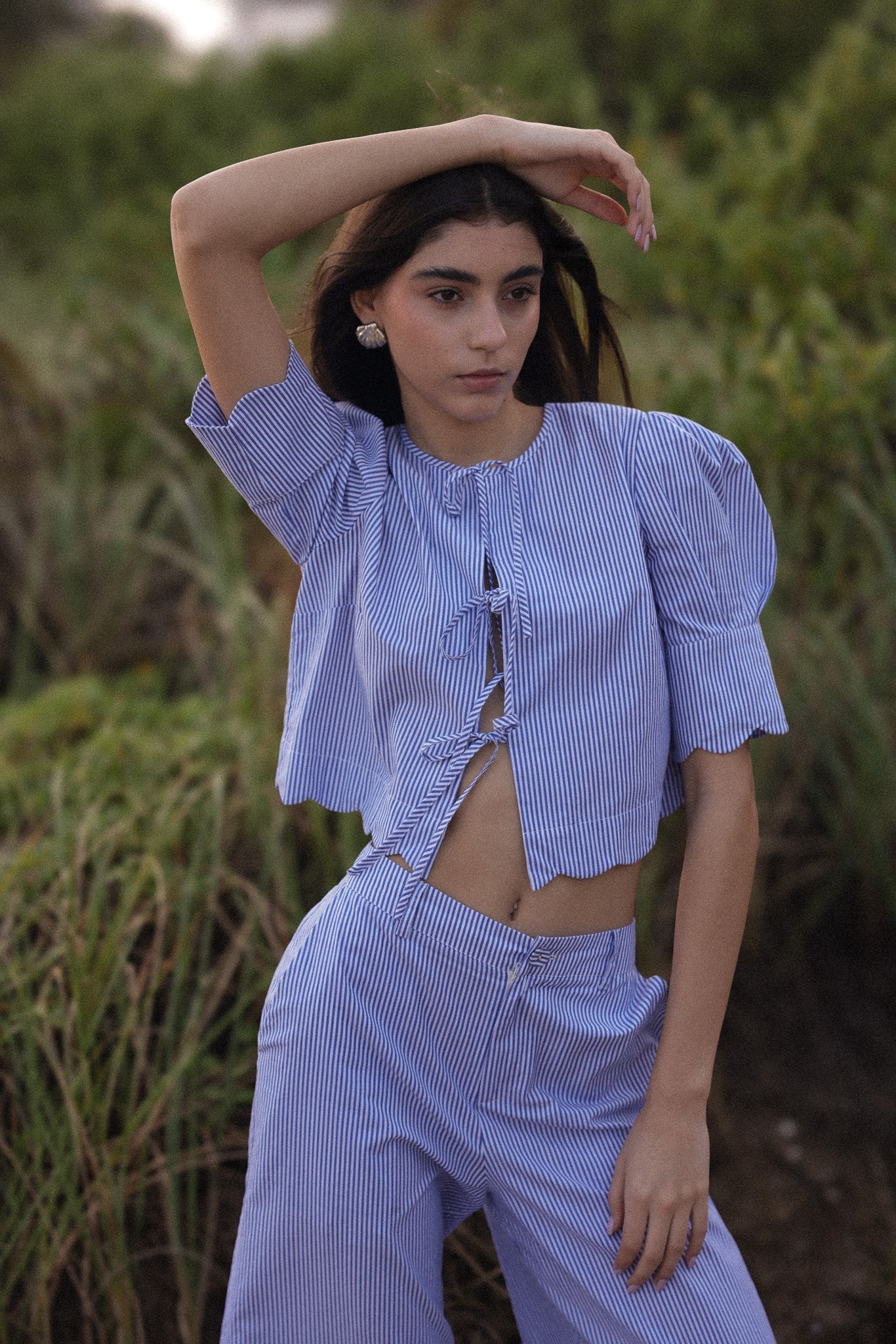 Woman wearing a blue checkered outfit standing in a natural setting
