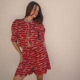 Woman wearing a red patterned outfit against a plain background