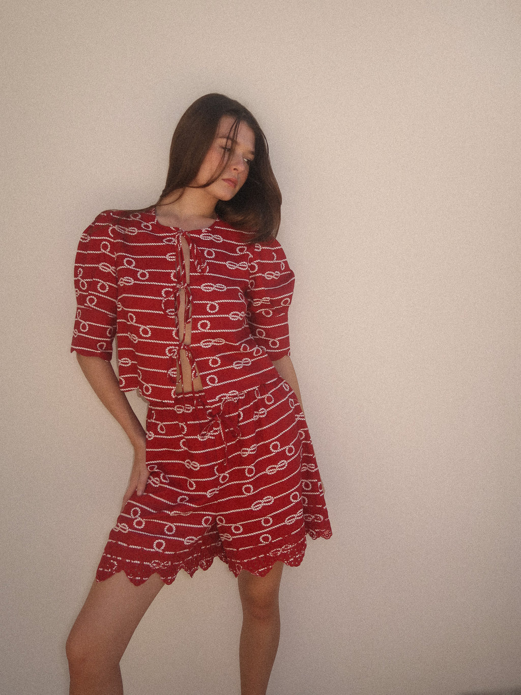 Woman wearing a red patterned outfit against a plain background