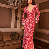 Woman in a red floral dress standing in a room with a chandelier and sofa.