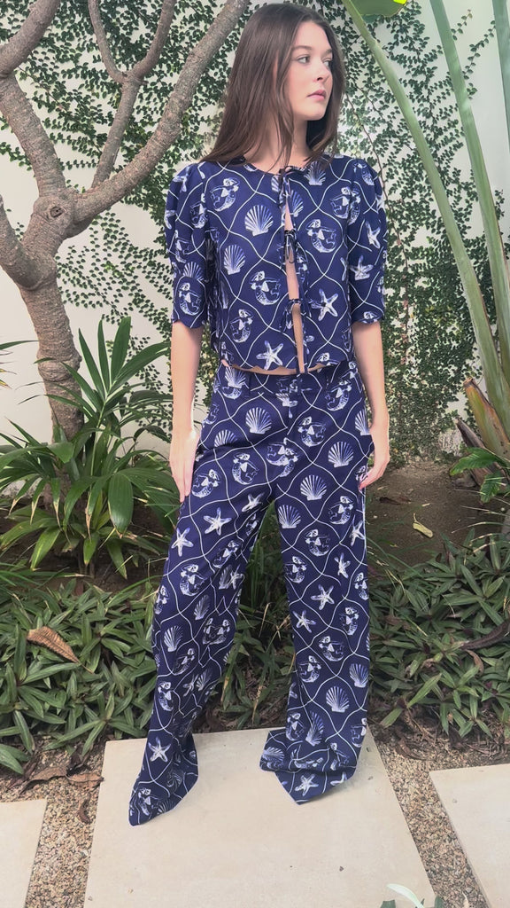 Woman modeling a blue printed linen set with matching top and pants in an outdoor setting