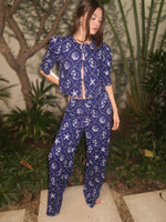Model wearing a blue printed pajama set with matching top and pants, standing outdoors